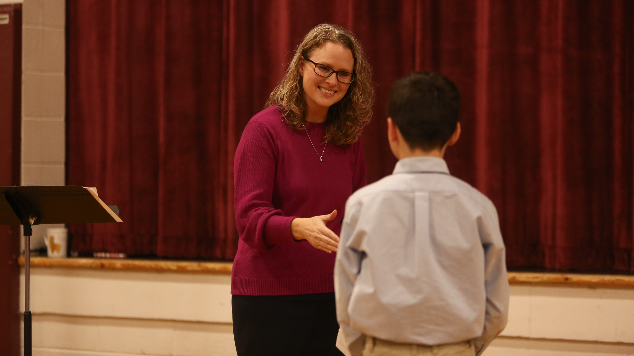 Teacher talks to her student during class presentations in the gymnasium