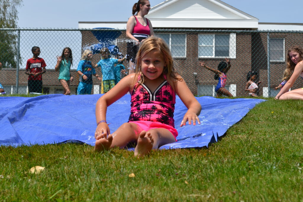 A girl in a pink bikini, attending a christian school, laying on a blue tarp.