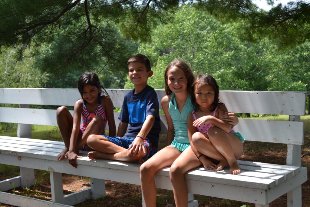 A group of Christian school kids sitting on a white bench.