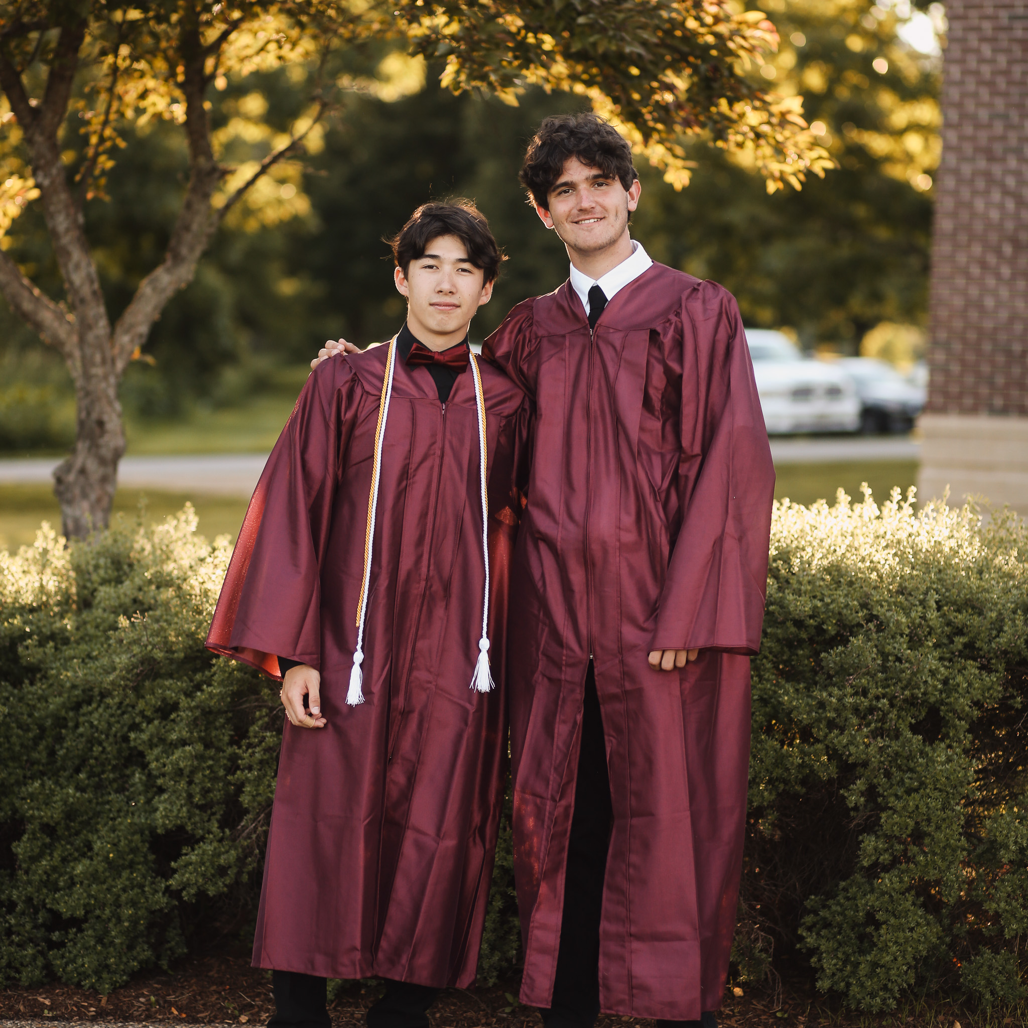 Two men in graduation robes from a Christian school posing for a picture.