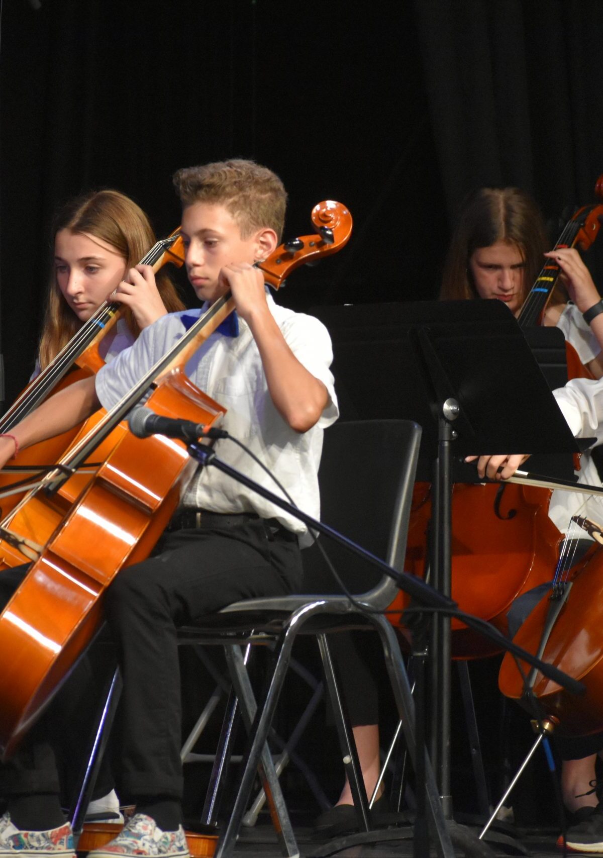 A group of children playing cellos on stage.
