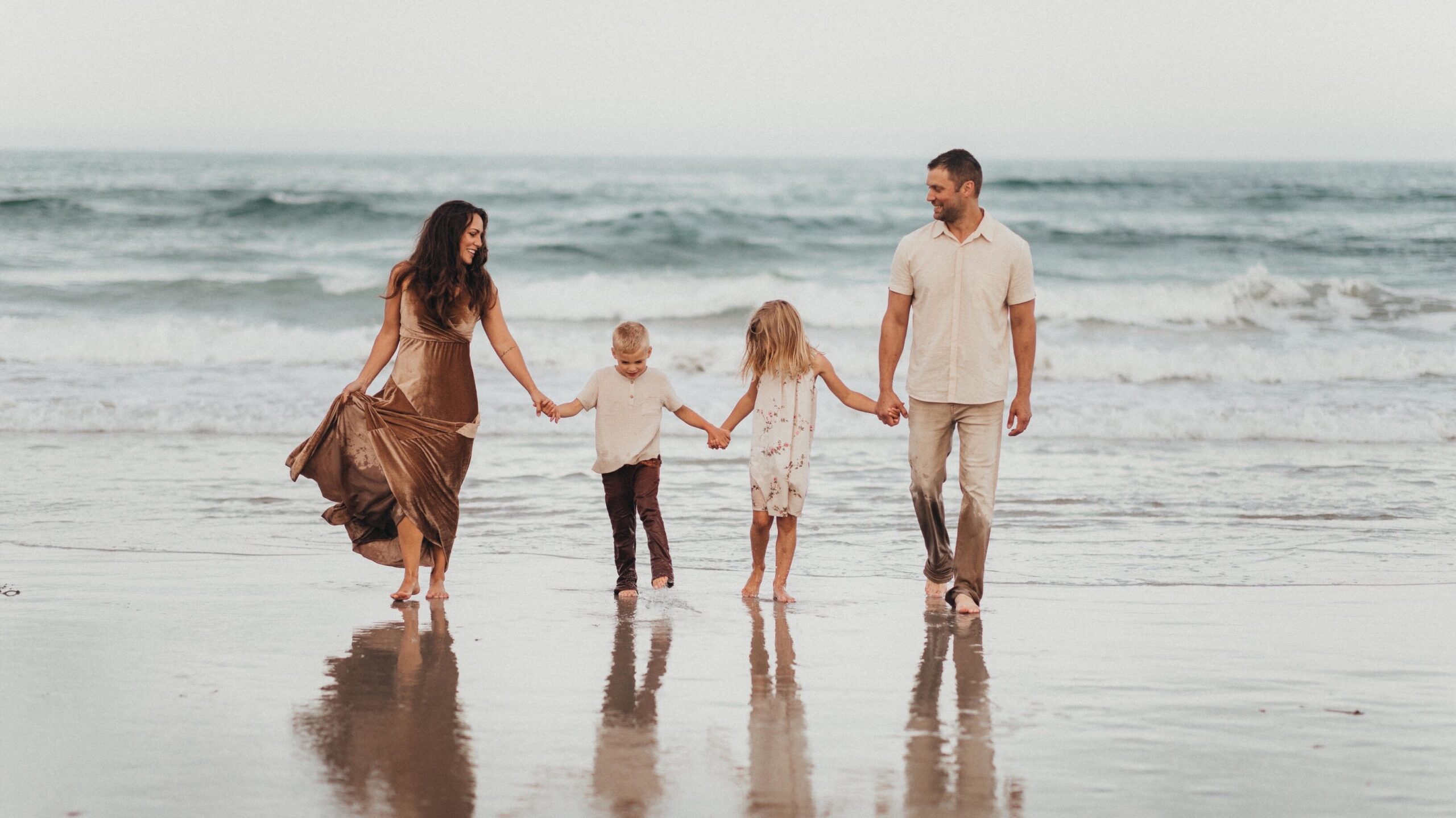         A Christian family walking on the beach holding hands.