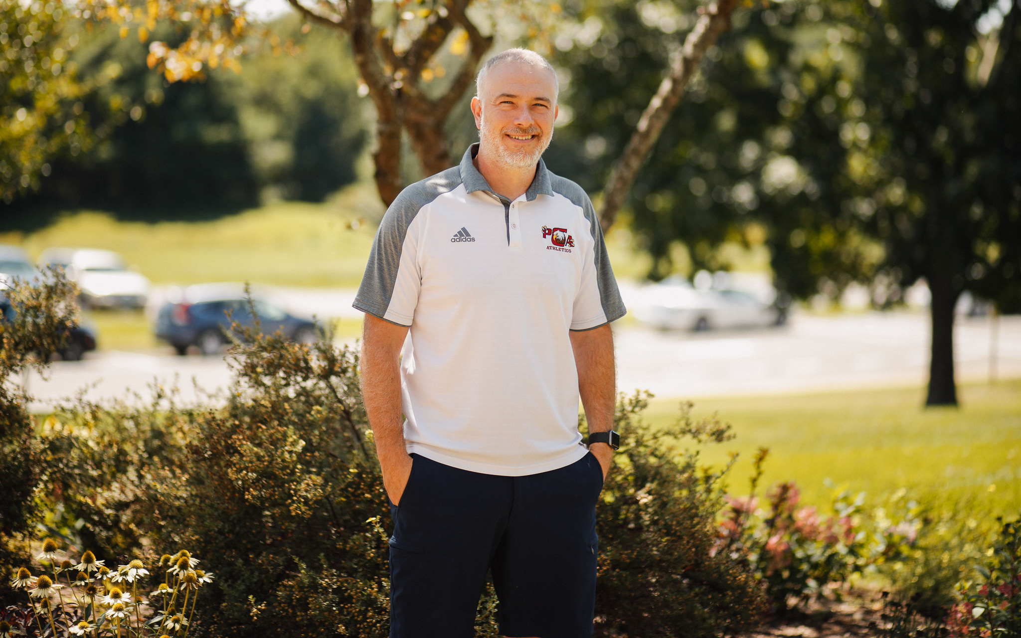 A man wearing a Hawaiian shirt attends his child's graduation ceremony at a Christian school.