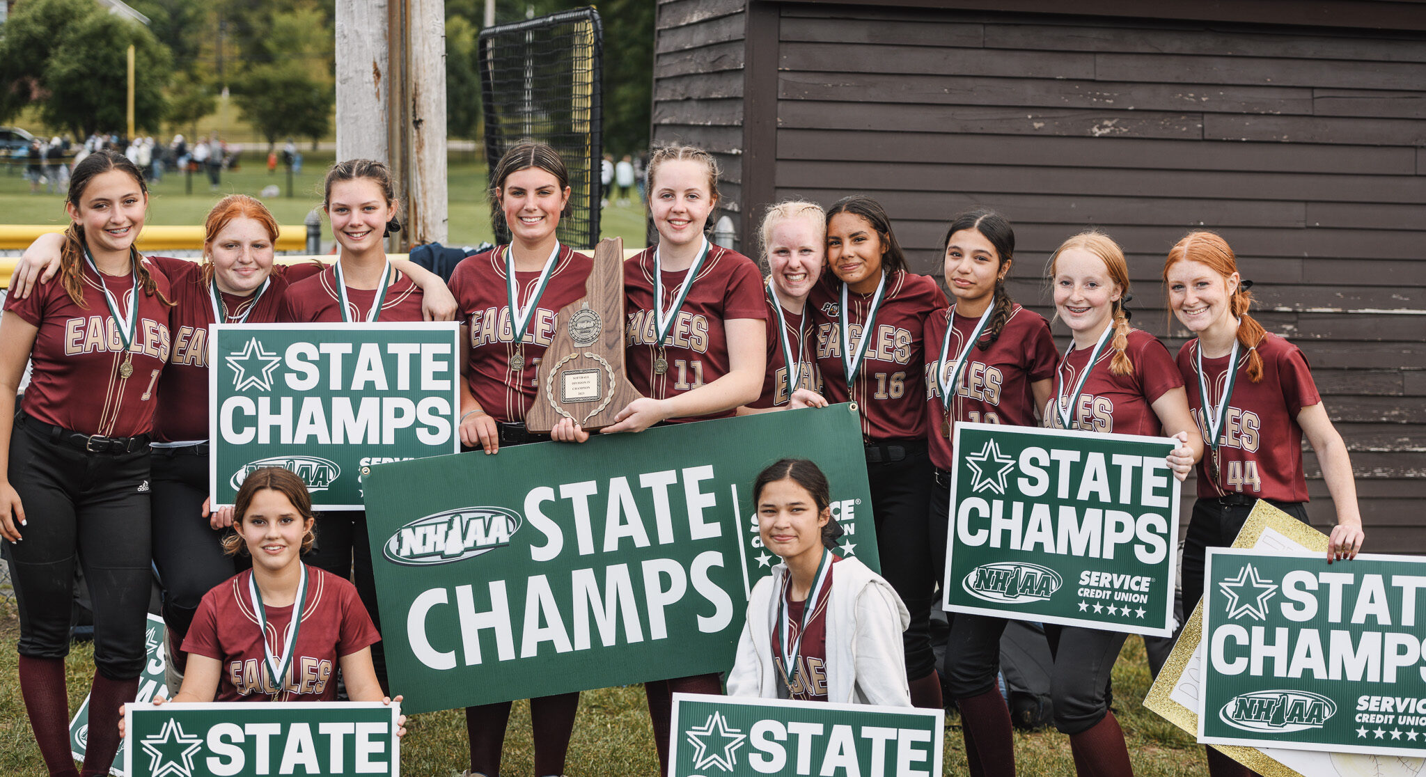 A group of softball players posing with their state championships.