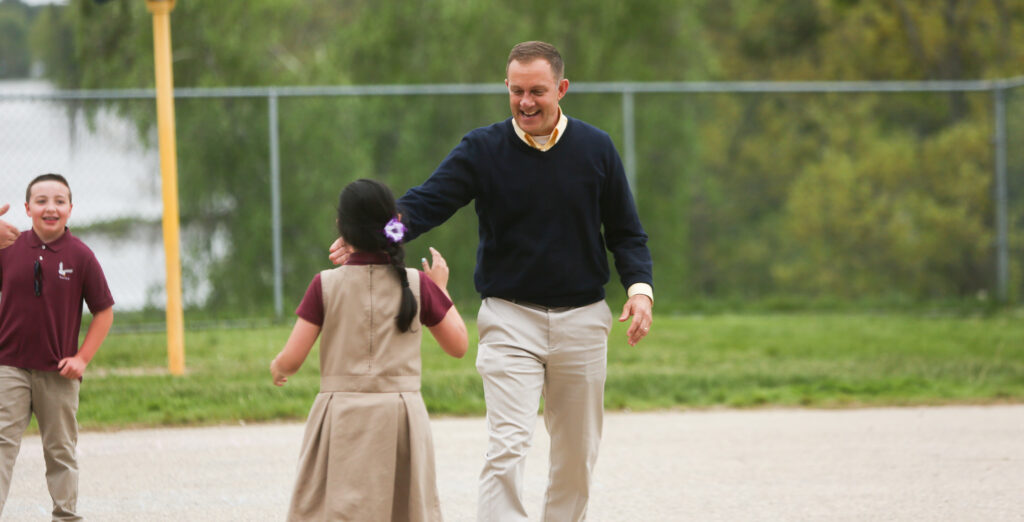 Head of School gives a student a high-five during a game on the playground