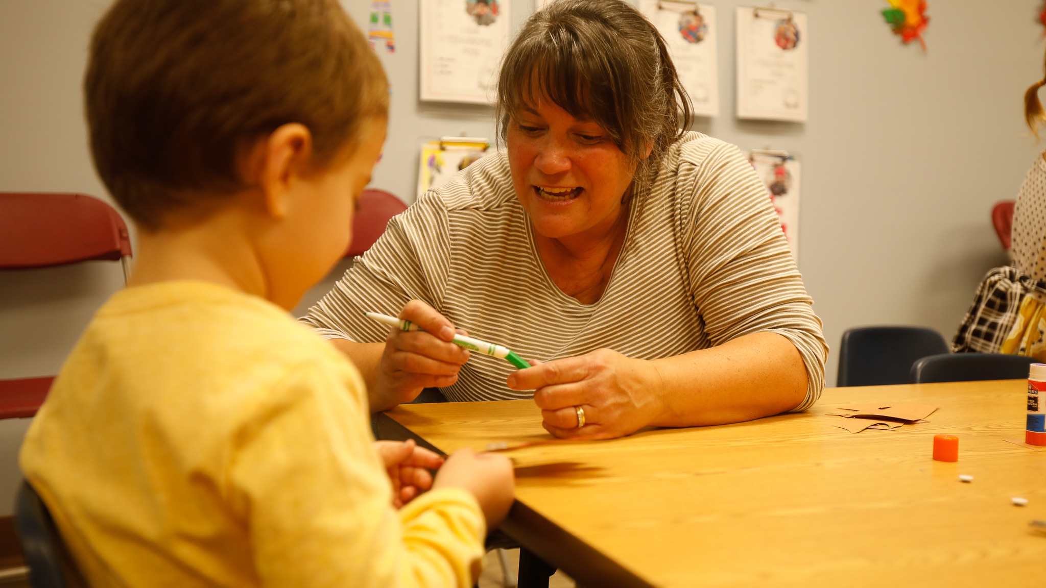 Preschool teacher works with her student on an art project