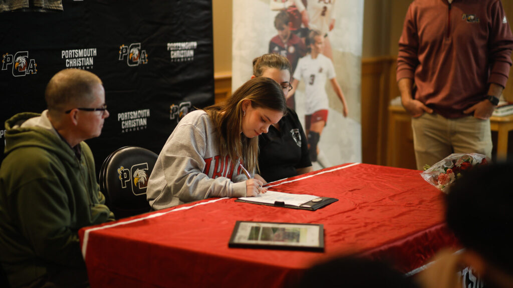 Photo of a high school girl signing her college letter of intent during her college signing day