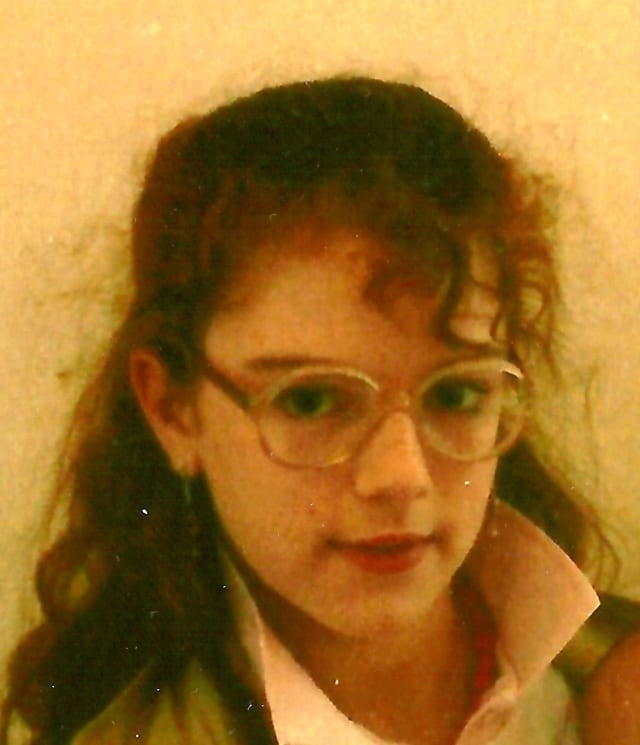 A young girl wearing glasses and a tie.